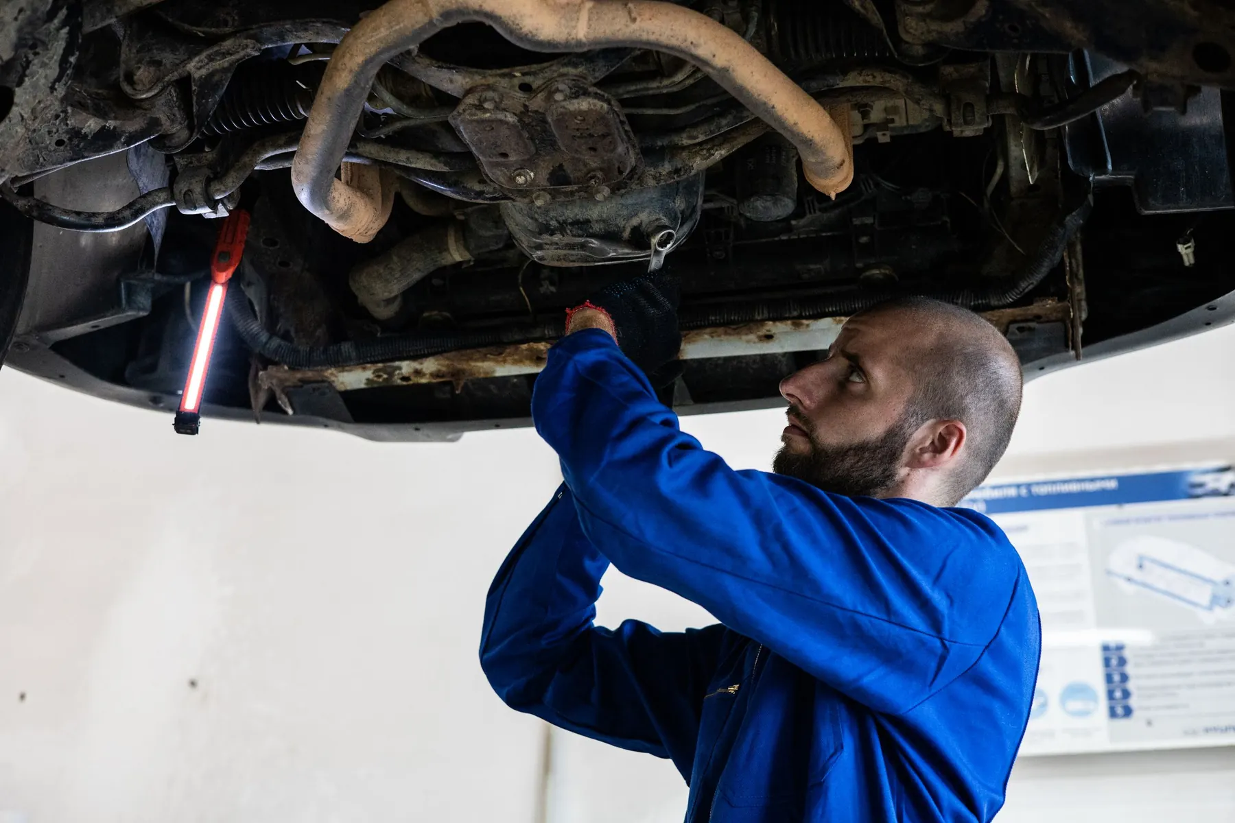 Mechanik kontroluje podvozek auta na zvedáku
